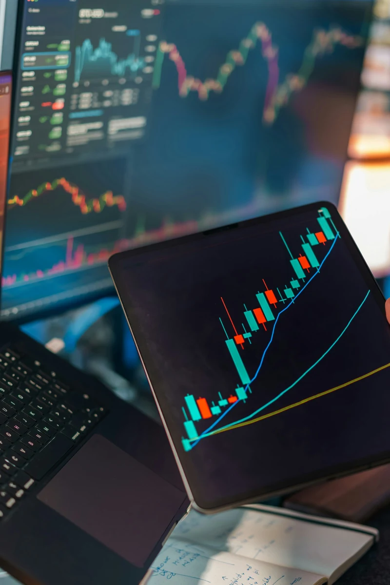 Financial charts displayed on a monitor and tablet; illustrative stock photograph.