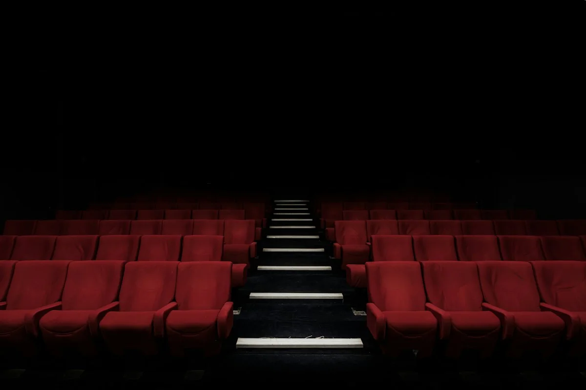 Realistic photograph of a laptop calendar beside cinema tickets and coffee on an adult desk, no legible screen text